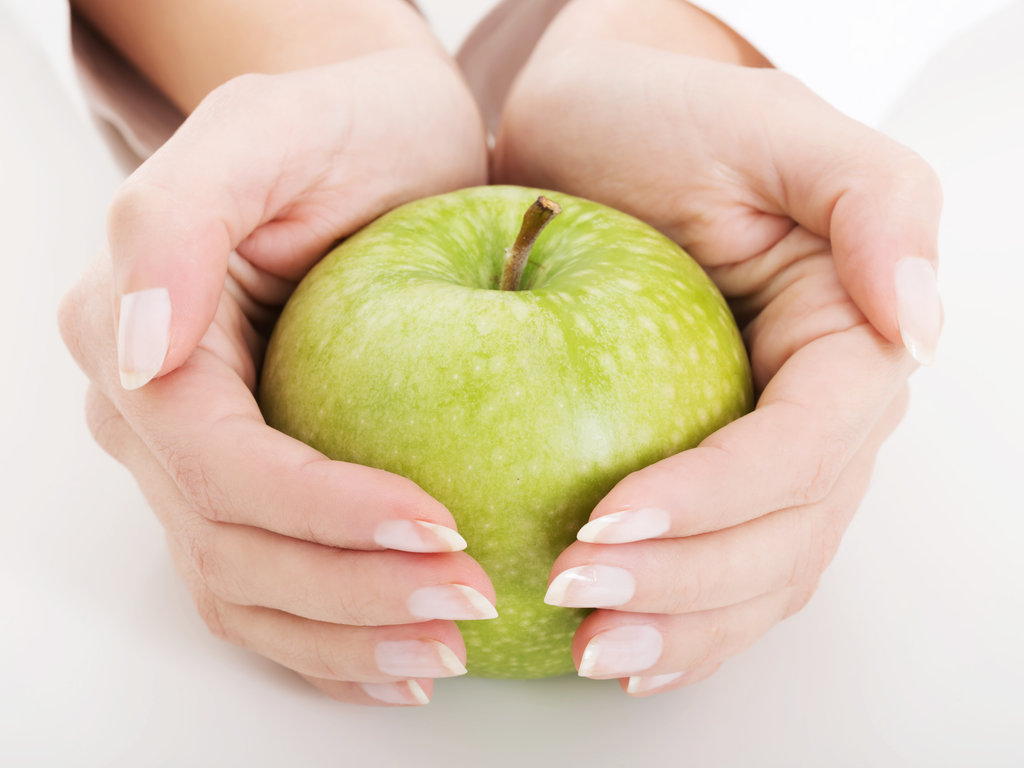 The big green apple in beautiful female hands.